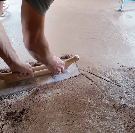 Des mains travaillent une surface de terre avec une taloche